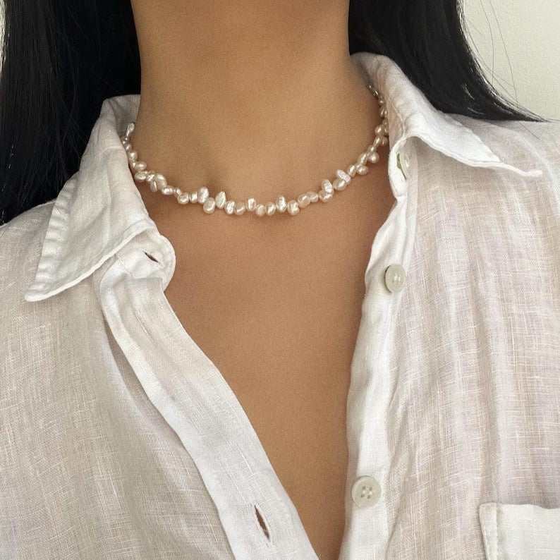 Close-up of a woman wearing an elegant natural pearl necklace with irregular freshwater pearls and a single-layer design