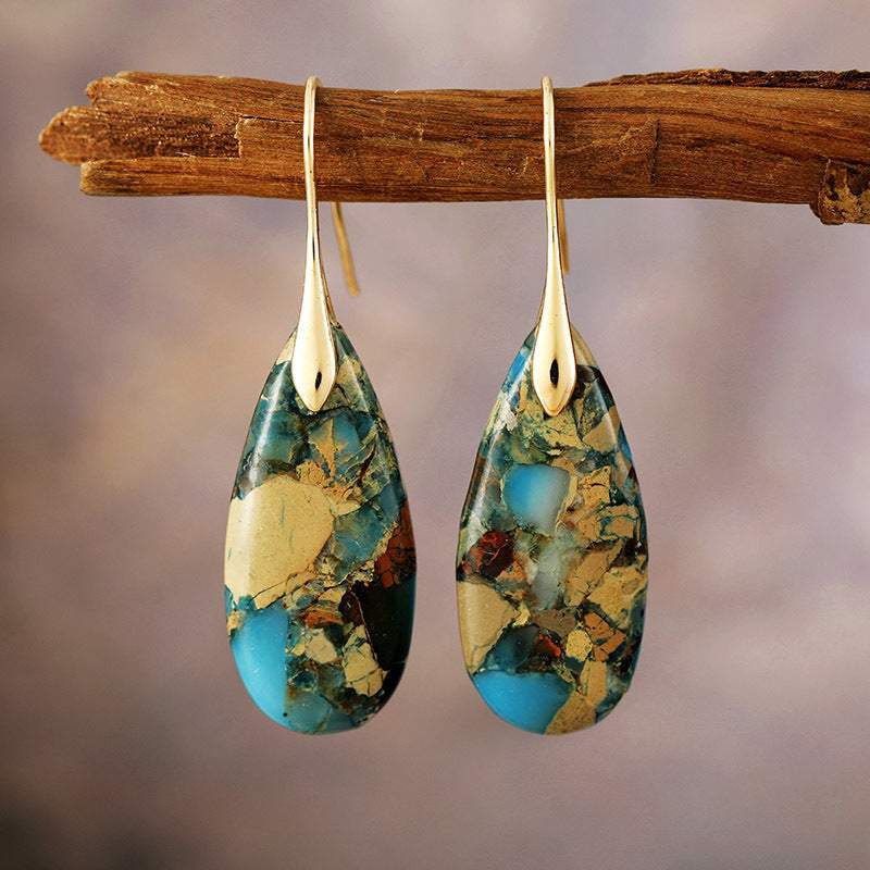 Bohemian Emperor Stone water drop pendant earrings with colorful stone pattern and gold hooks hanging on a wooden branch