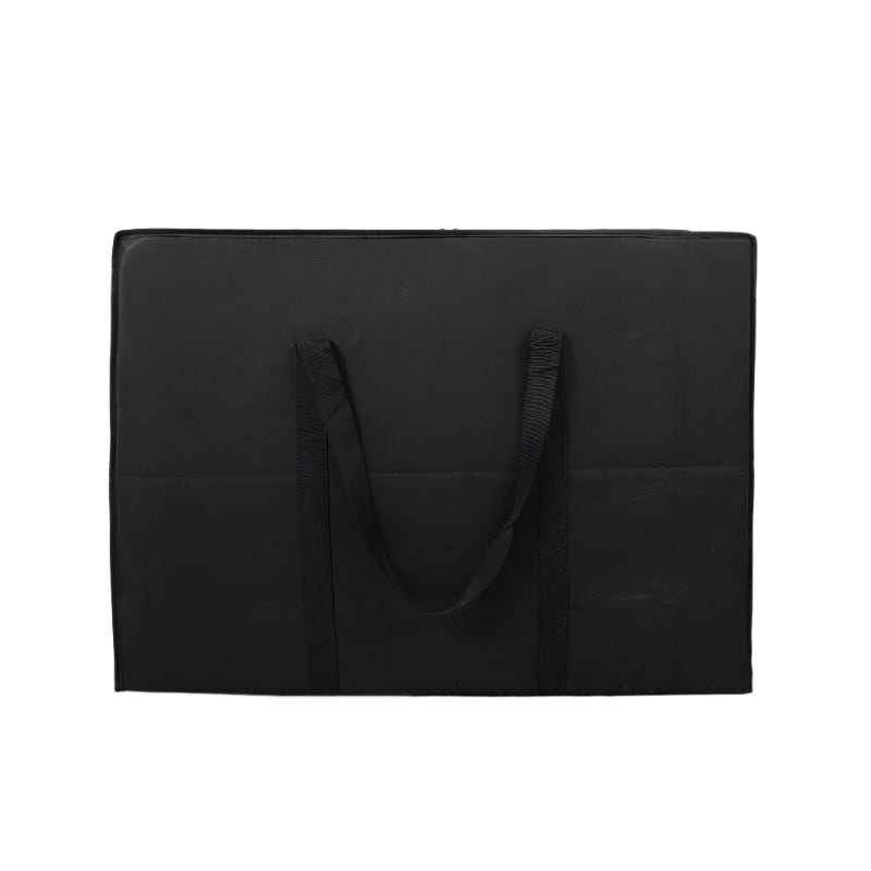 Black dormitory packing bag made of non-woven fabric on wooden floor.