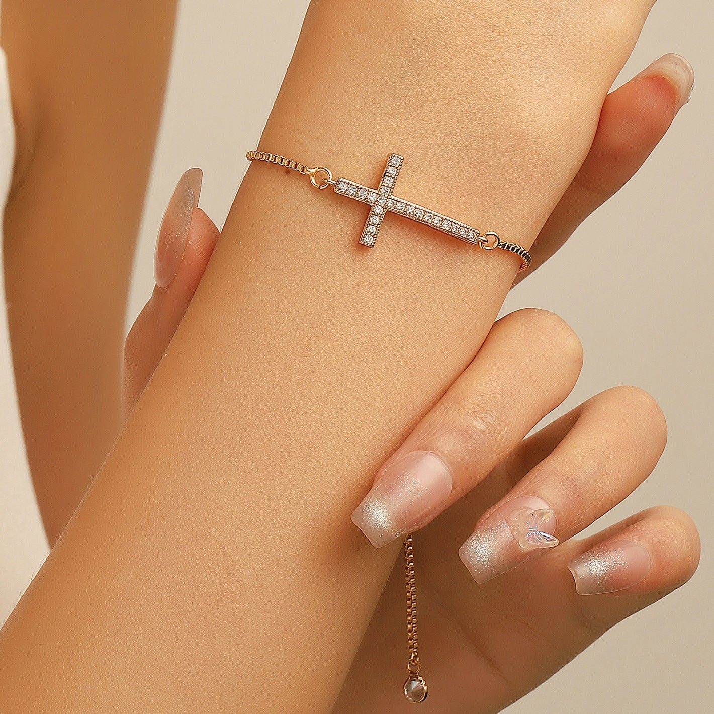 Women's diamond pull-out cross bracelet on wrist with delicate chain and elegant design