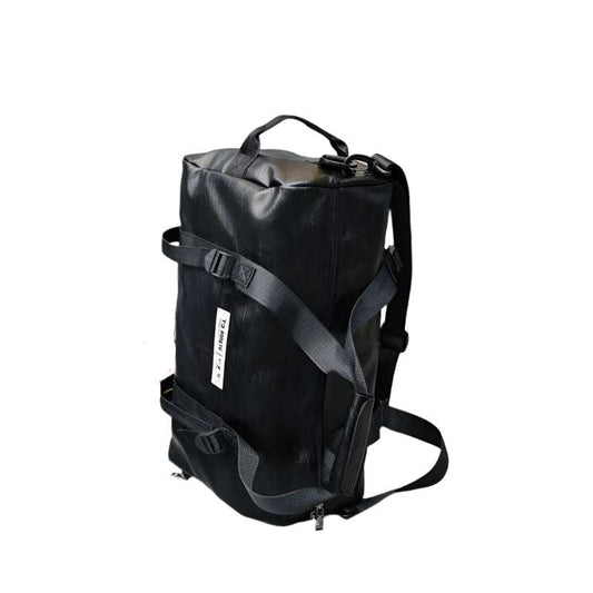 Black portable travel bag with adjustable straps and skateboard in the background.