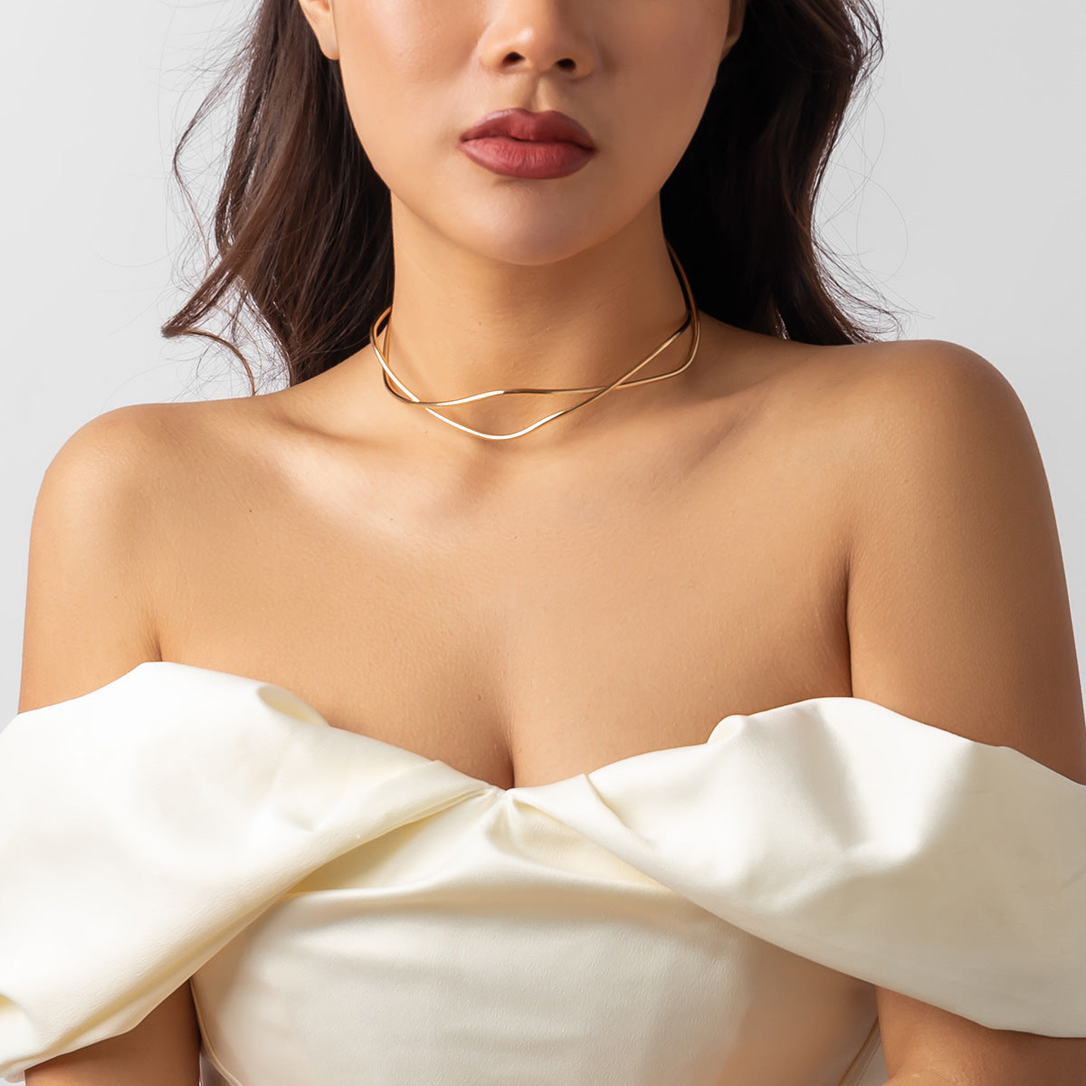 Female model wearing a gold simple clavicle chain open line geometric neck ring with off-shoulder white dress