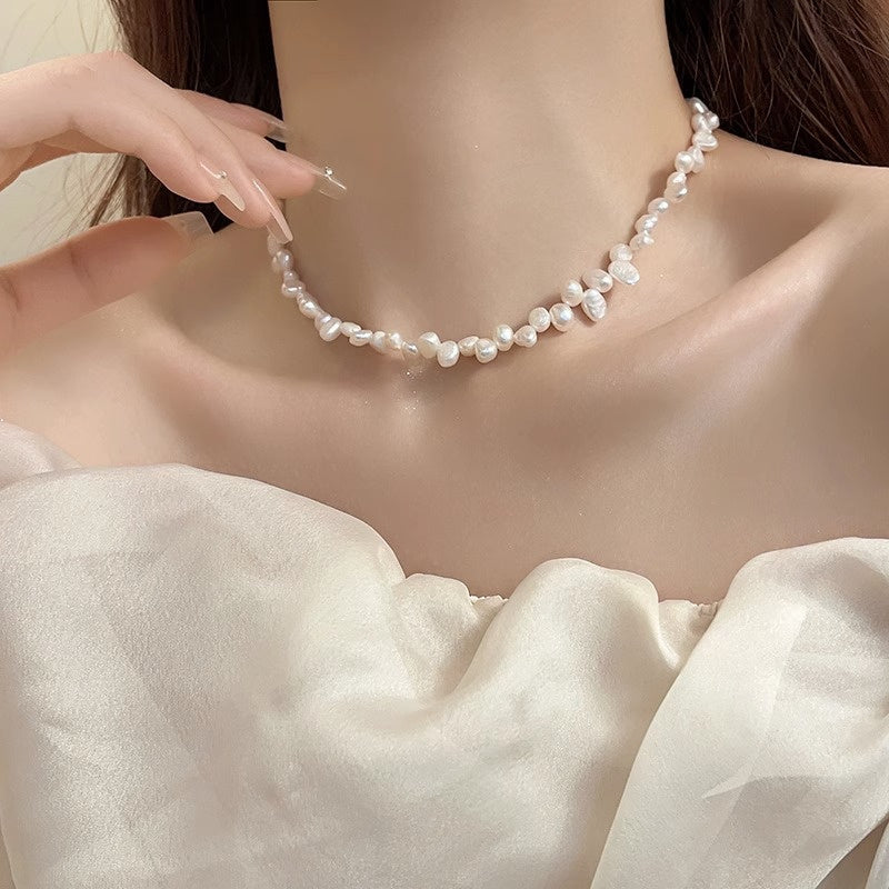 Close-up of a woman wearing an irregular freshwater natural pearl necklace with geometric-shaped pearls and a white off-shoulder top