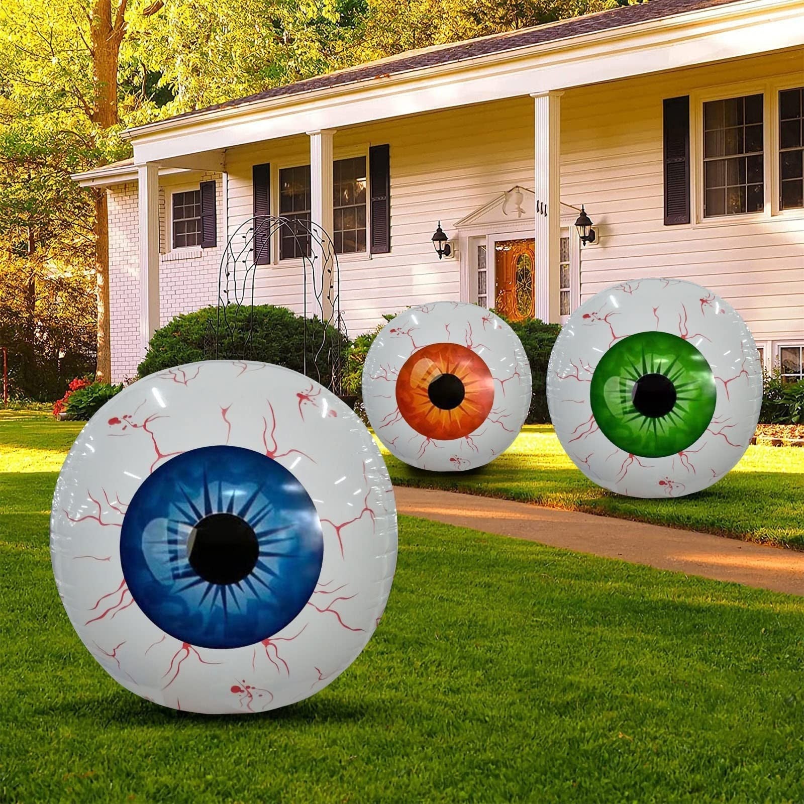 Inflatable Halloween eyeball balloons in blue, orange, and green with bloodshot design displayed as outdoor Halloween decorations.
