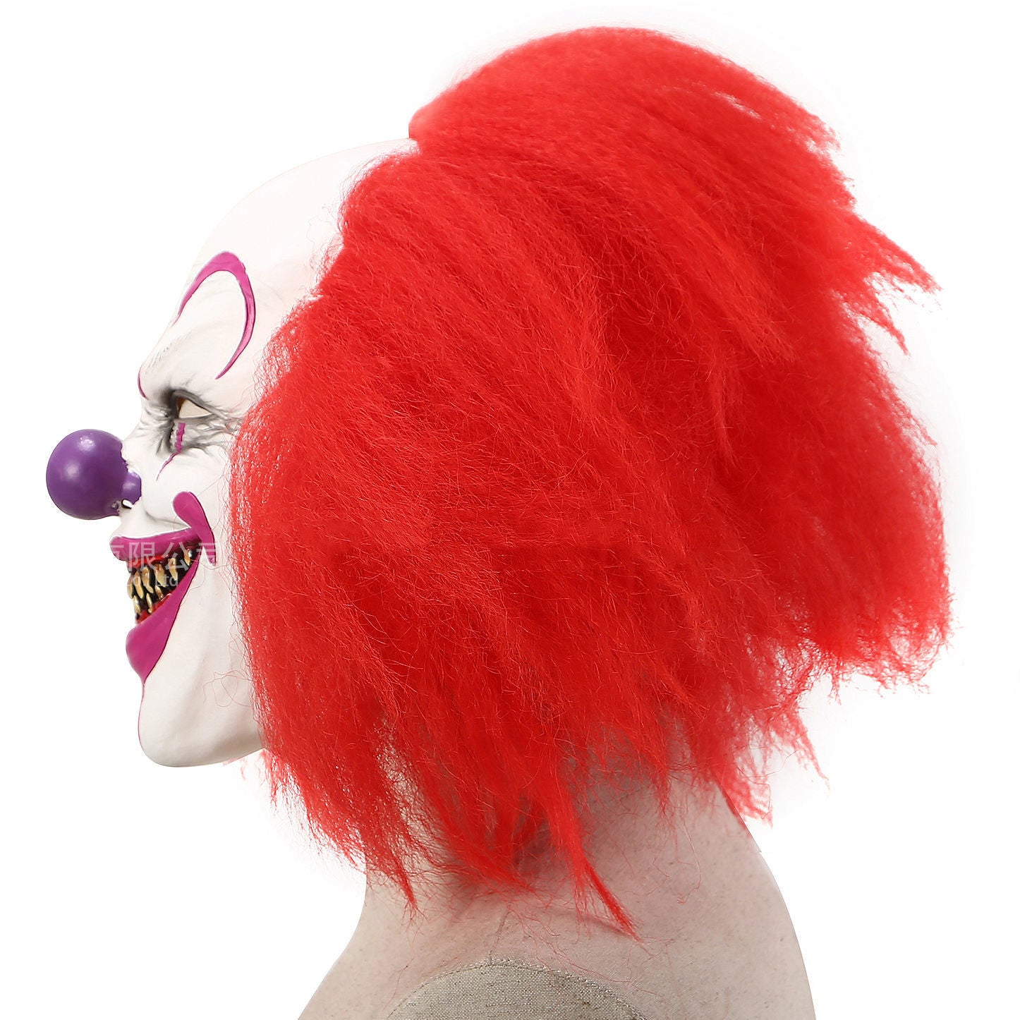 Side angled view of a clown mask with red hair and a purple ball on a white background